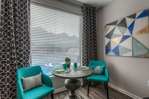 Lenexa apartment for rent - a small dining table with two blue chairs and a large window with blinds  at EdgeWater at City Center, Lenexa, KS