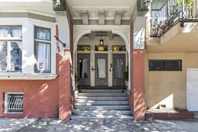 San Francisco apartment for rent - A red brick building with a white door and a window with a white curtain.