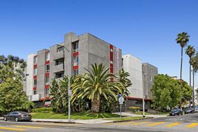 Los Angeles apartment for rent - a building with palm trees in front of it on a city street