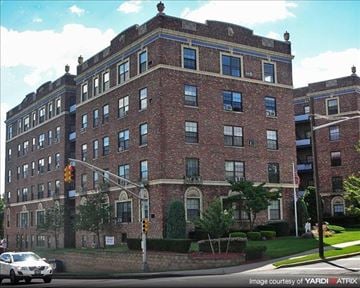Hackensack apartment for rent - A red brick building with a white car parked in front.