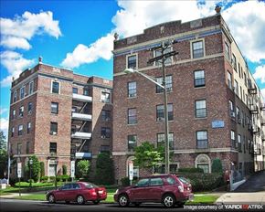 Hackensack apartment for rent - A red car is parked in front of a brick building.