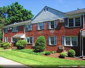 Bound Brook apartment for rent - A red brick house with a white roof and a green lawn in front.