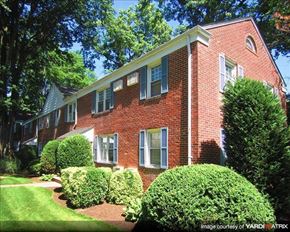 Bound Brook apartment for rent - A red brick house with green bushes in front.