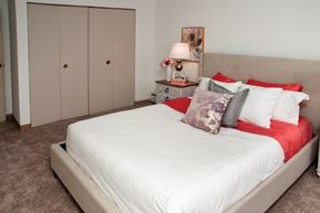 Bloomington apartment for rent - a bedroom with a white bed and red pillows
