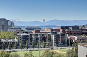 Seattle apartment for rent - A cityscape with a large building in the foreground and mountains in the background.