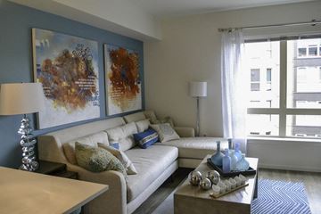 Seattle apartment for rent - A living room with a white couch and a coffee table with blue vases on it.
