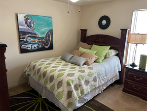 Bentonville apartment for rent - a bedroom with a bed and a painting of a car on the wall