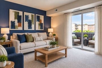 Glen Burnie apartment for rent - A living room with a blue couch, a wooden coffee table, and a painting on the wall.