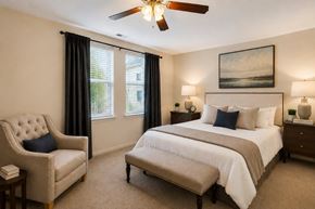 Baltimore apartment for rent - A bedroom with a large bed, a chair, and a ceiling fan.