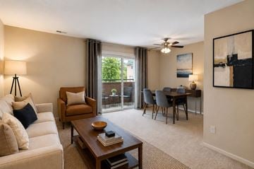 Baltimore apartment for rent - A living room with a white couch, a brown armchair, a wooden coffee table, and a dining table with chairs.