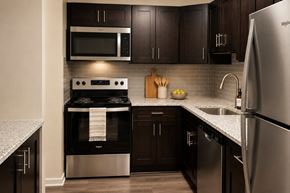 Baltimore apartment for rent - A modern kitchen with dark wood cabinets and stainless steel appliances.