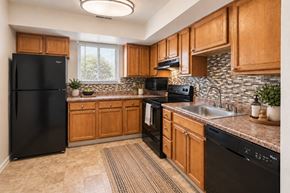Westminster apartment for rent - A kitchen with wooden cabinets and black appliances.