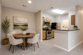 Garner apartment for rent - A dining room with a table and chairs and a kitchen in the background.