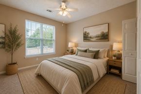 Garner apartment for rent - A bedroom with a large bed, a ceiling fan, and a painting on the wall.