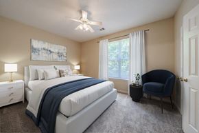 Raleigh townhouse for rent - A bedroom with a large bed, a chair, and a painting on the wall.