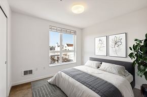 Seattle apartment for rent - Bright bedroom at 4400 Alaska featuring a queen bed, large window with blinds, and a sliding closet.