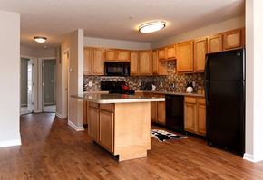 York apartment for rent - a kitchen with wooden cabinets and a black refrigerator