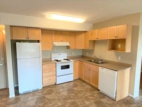 Brandon apartment for rent - an empty kitchen with white appliances and wooden cabinets