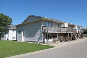 Brandon triplex for rent - a gray house with a porch and a street in front of it