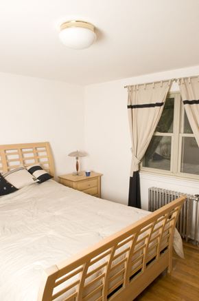 Fair Lawn triplex for rent - A bedroom with a bed, nightstand, and window.