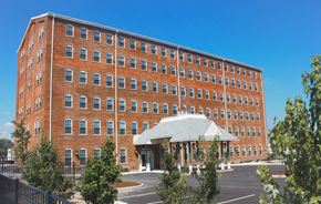 Connersville apartment for rent - A large red brick building with a white roof and a black fence in front.