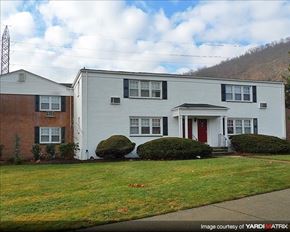 Suffern apartment for rent - A white house with a red door is situated in front of a brown house.