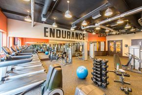 Washington apartment for rent - a gym with weights and cardio machines and a sign on the ceiling that reads endurance