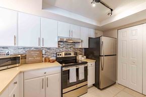 Boca Raton apartment for rent - A kitchen with white cabinets and a black fridge.