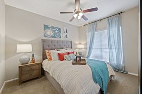 Dallas apartment for rent - a bedroom with a large bed and a ceiling fan