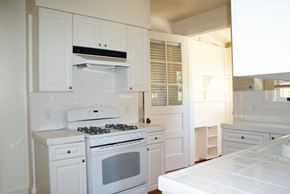 San Francisco triplex for rent - a small kitchen with white cabinets and a white stove and oven