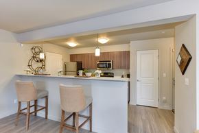 Renton apartment for rent - Model Kitchen with Counter,Stools, Hardwood Inspired Floor, Ceiling Lights, and Fridge/Freezer