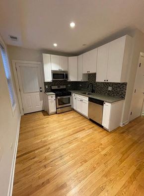 Chicago apartment for rent - an empty kitchen with white cabinets and a wood floor