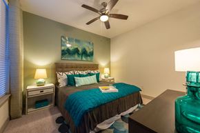 Houston apartment for rent - A bedroom with a bed, nightstands, and a ceiling fan.