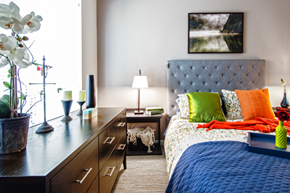 Seattle apartment for rent - a bedroom with a bed with colorful pillows and a dresser