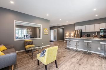 Okemos townhouse for rent - A modern kitchen with a bar area and a dining table with chairs.