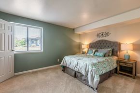 Okemos townhouse for rent - A bedroom with a bed, nightstand, and window.