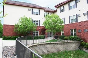 St Cloud apartment for rent - A white building with a red brick wall and a black fence.