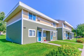 Albany townhouse for rent - the exterior of two houses with green and brown siding and a green lawn