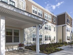 South Berwick apartment for rent - A building with a white porch and a bench in front.