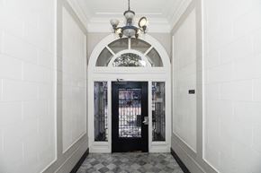 San Francisco apartment for rent - A black door is at the end of a hallway with white walls.