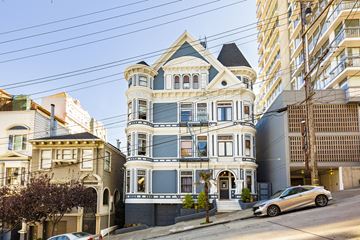 San Francisco apartment for rent - A large, ornate Victorian-style house sits on a street corner with a modern building in the background.