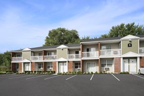 Cohoes apartment for rent - an exterior view of an apartment building with a parking lot