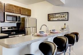 Portage apartment for rent - a kitchen with a counter with chairs and a sink and a refrigerator