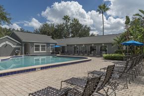 Orlando apartment for rent - a swimming pool with chairs and a building in the background