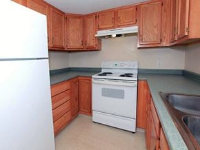 Fall River apartment for rent - a kitchen with wooden cabinets and a white stove and refrigerator