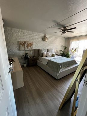 Tucson apartment for rent - A bedroom with a bed, a ceiling fan, and a white brick wall.