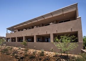 Tucson apartment for rent - an image of the back of a building with trees and bushes