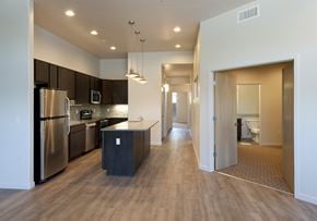 Tucson apartment for rent - a kitchen with stainless steel appliances and a long hallway with a door to a bathroom
