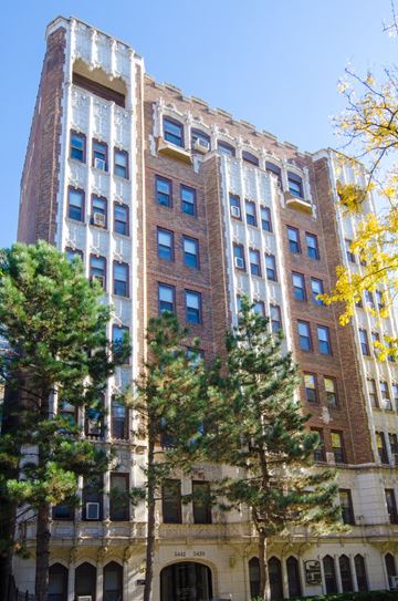 Chicago apartment for rent - a tall brick building with trees in front of it