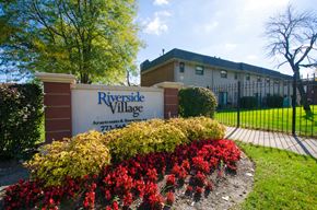 Chicago apartment for rent - A sign for Riverside Village Apartments stands in front of a building.